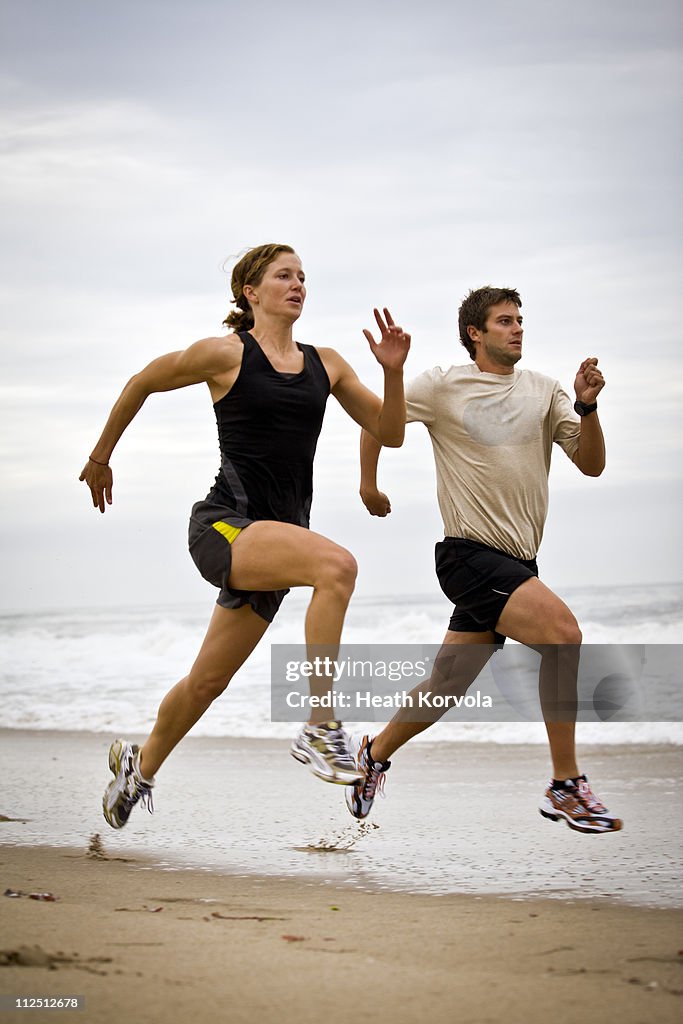 Man and woman running (striding) on beach.