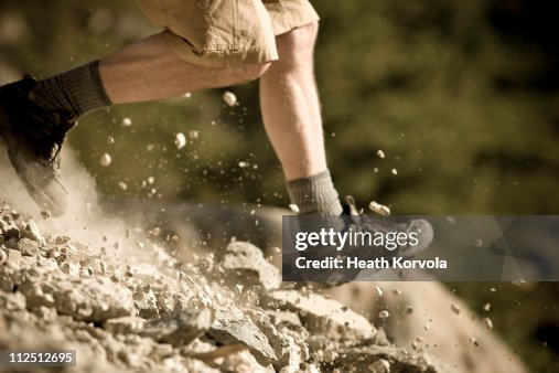 Man in shorts running off trail downhill.
