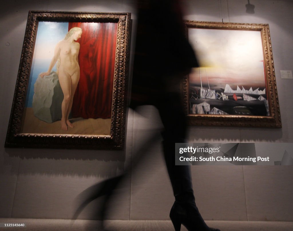 A visitor walks past the paintings (L) "L'aimant" by Ren?? Magritte, estimated ?˙3,500,000-5,500,000; and (R) "Je me faisais semblant (I was Pretending to myself)" by Yves Tanguy, estimated ?˙2,000,000-3,000,000, during the press preview of Christie's th
