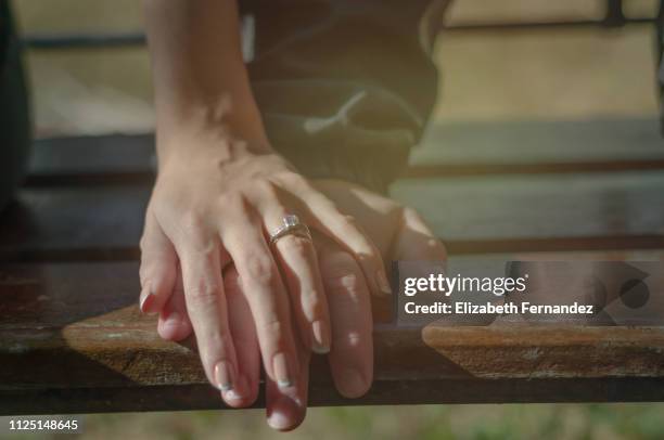 couple holding hands, woman wearing engagement ring. - alliance mariage stock-fotos und bilder