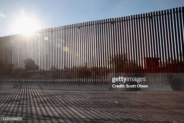 The sun rises behind a steel and concertina wire barrier that runs behind a shopping mall along the border of the United States and Mexico on January...