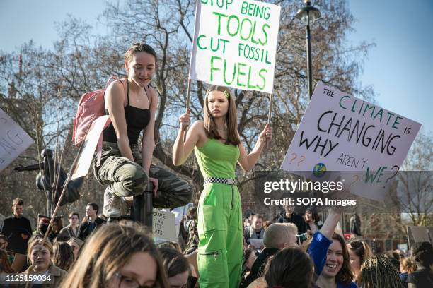 Perched on bollards, participants to the first UK school strike against climate change hold their banners. Thousands of primary school children,...