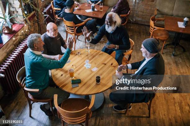 two mature friends high-five during card game - senior men playing cards stock pictures, royalty-free photos & images