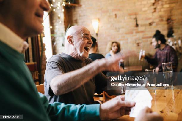 old man laughing during card game - tischflächen aufnahme stock-fotos und bilder