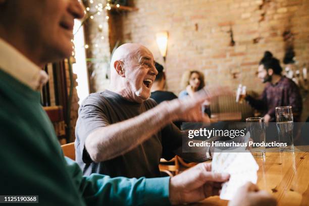 old man laughing during card game - friends bar stock pictures, royalty-free photos & images