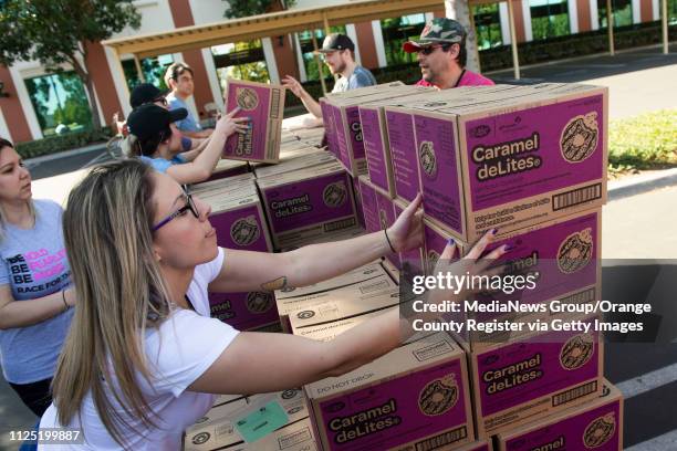 Volunteer Katie O'Neill of Orange, and several of her First American Title co-workers stack Caramel deLites as they load up vehicles during the Girl...