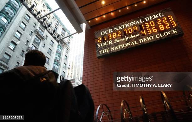 Man walks past the he National Debt Clock on 43rd Street in midtown New York City February 15, 2019. - The National Debt Clock is a billboard...