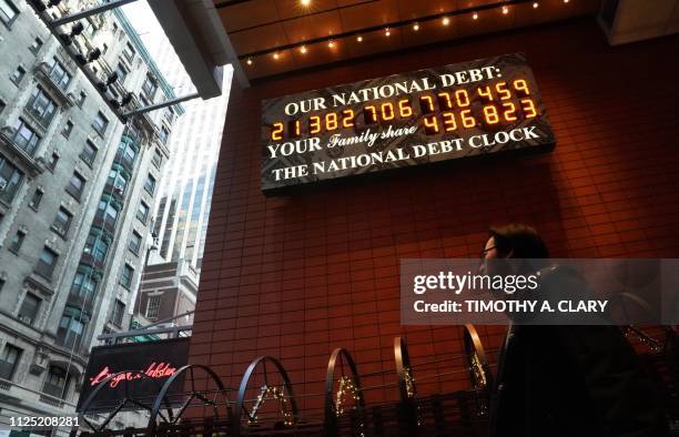 Man walks past the he National Debt Clock on 43rd Street in midtown New York City February 15, 2019. - The National Debt Clock is a billboard...