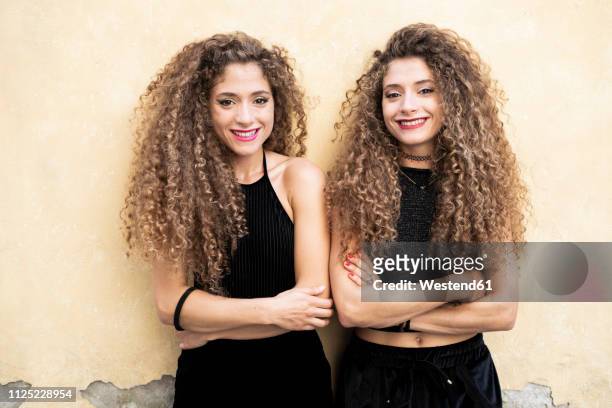 portrait of laughing twin sisters standing side by side - twin stock pictures, royalty-free photos & images