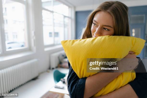 smiling young businesswoman with yellow pillow in office - pillow stock pictures, royalty-free photos & images