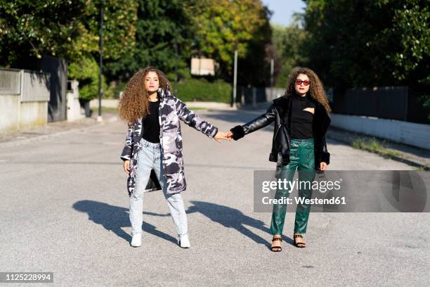 portrait of fashionable twin sisters holding hands - snakeskin stock pictures, royalty-free photos & images