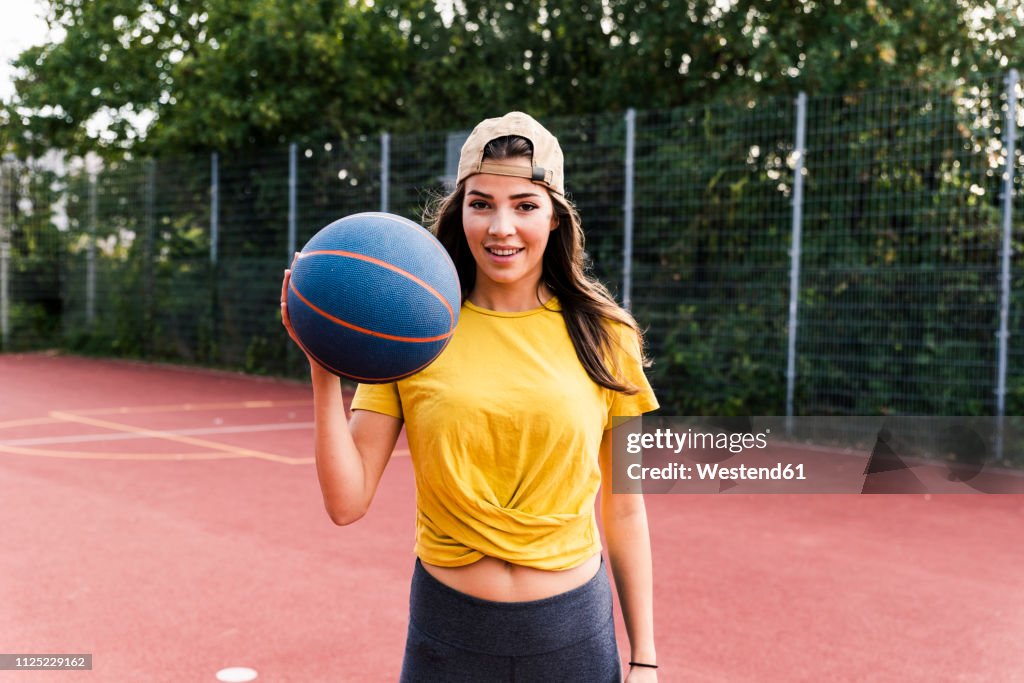 Happy young woman playing basketball