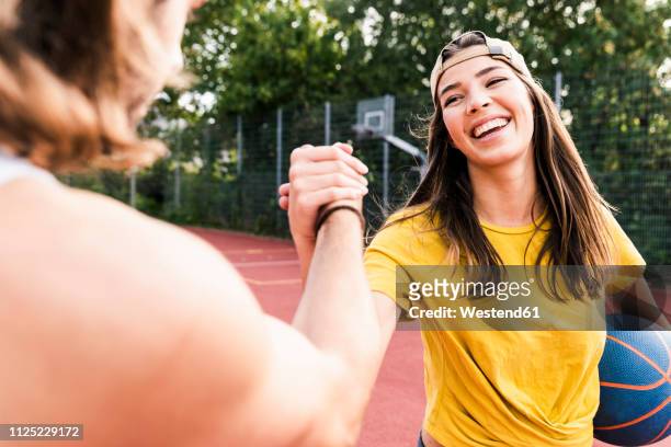 young man and young woman high-fiving after basketball game - active lifestyle stock-fotos und bilder