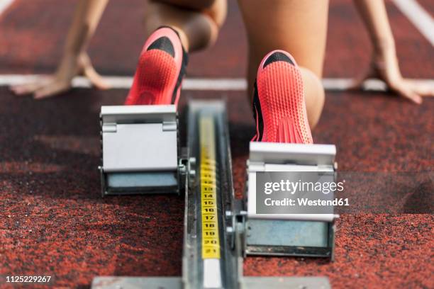 teenage runner kneeling on starting block, close up - track starting block stock pictures, royalty-free photos & images