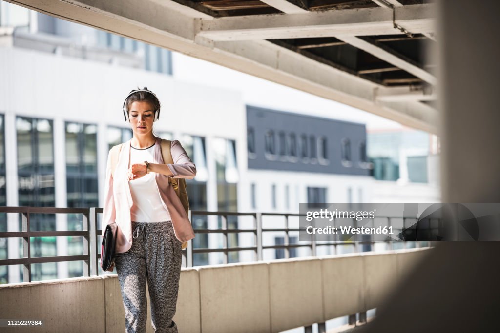 Young businesswoman walking in parking garage, checking time