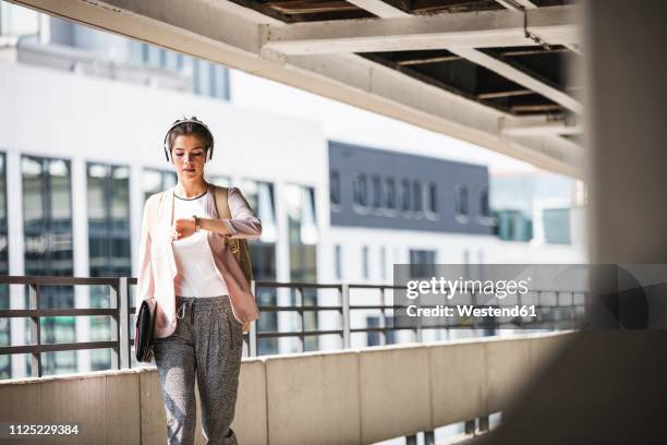 young businesswoman walking in parking garage, checking time - woman hurry 個照片及圖片檔