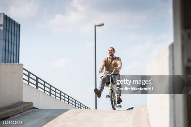 laughing businessman riding down a ramp on his bicycle - mobility stock-fotos und bilder