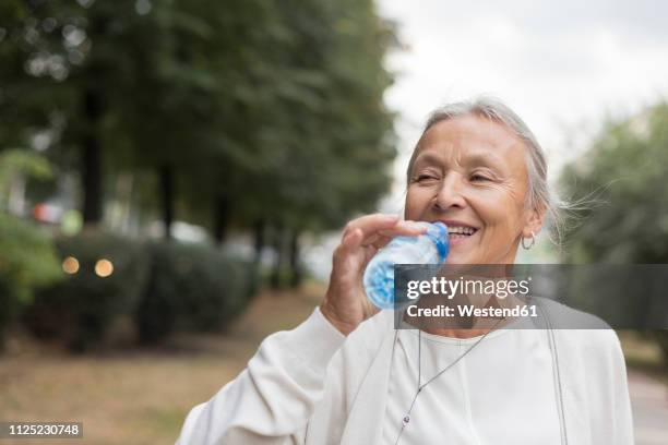 happy senior woman outdoors drinking water from bottle - törstig bildbanksfoton och bilder