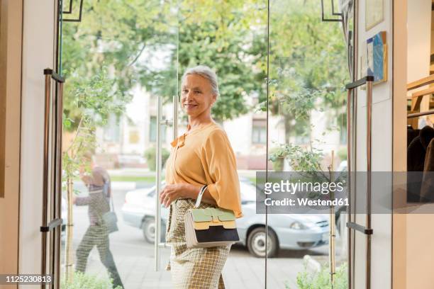 smiling senior woman walking along a boutique - boutique entrance stock pictures, royalty-free photos & images