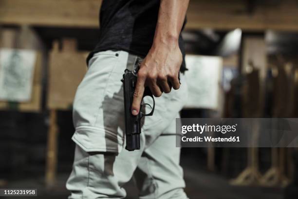 close-up of man holding a pistol in an indoor shooting range - 拳銃 ストックフォトと画像