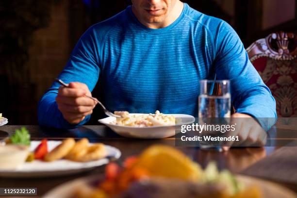 close-up of athlete eating pasta dish - mann wasser trinken sport stock-fotos und bilder