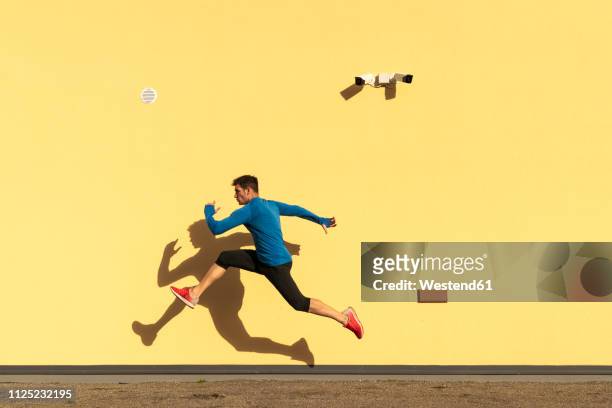 sportive man exercising at yellow wall with cctv camera - man sprinting stock pictures, royalty-free photos & images