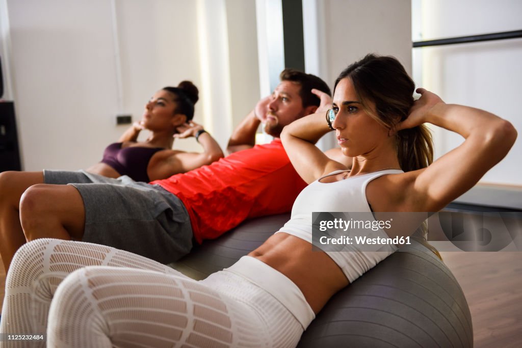 Young people doing crunches on a gym ball