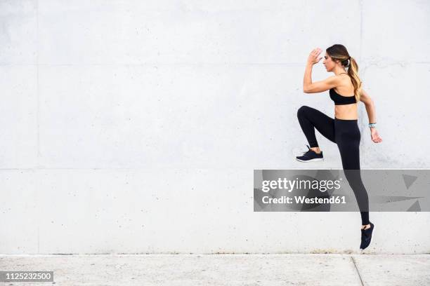 athlete jumping in front of white wall - ropa de deporte fotografías e imágenes de stock