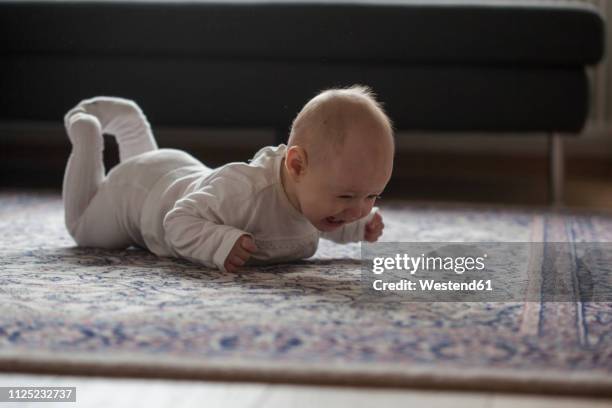 screaming baby girl lying on carpet - lying on front stock pictures, royalty-free photos & images