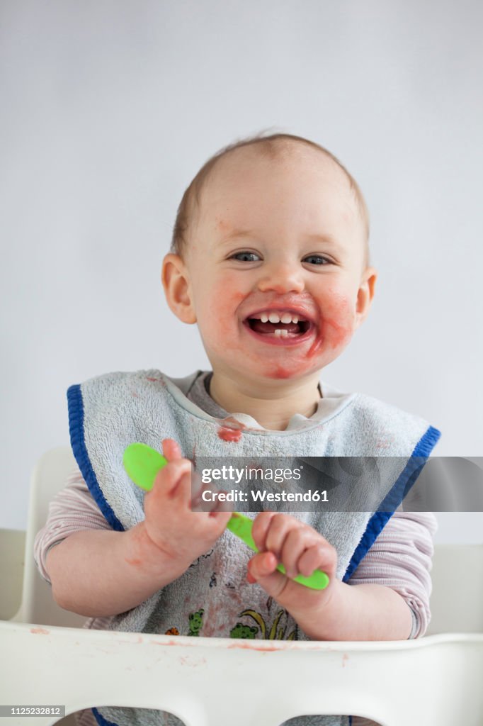 Portrait of happy baby girl with smeared face on high chair