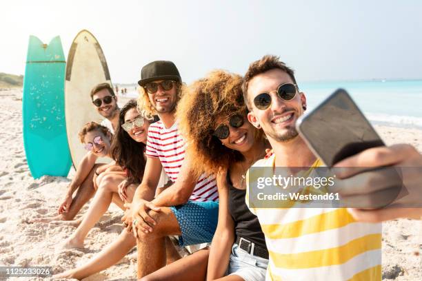 friends sitting on the beach, having fun, taking selfies - all men group selfie stock pictures, royalty-free photos & images