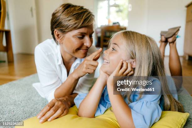 happy mother and daughter lying on the floor at home - girl hold nose stock pictures, royalty-free photos & images