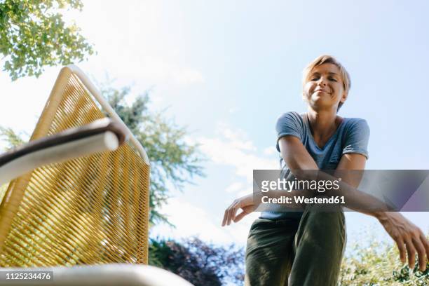 portrait of smiling woman in garden next to chair - low angle view stock pictures, royalty-free photos & images