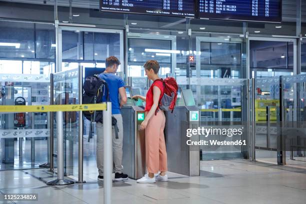 couple passing security gate at the airport - douane stockfoto's en -beelden
