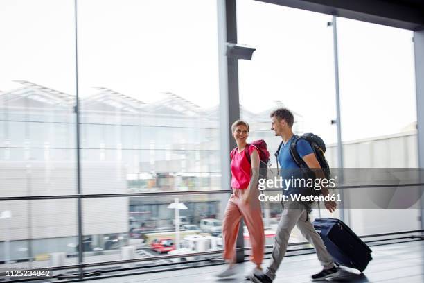 smiling couple walking at the airport - abheben aktivität stock-fotos und bilder