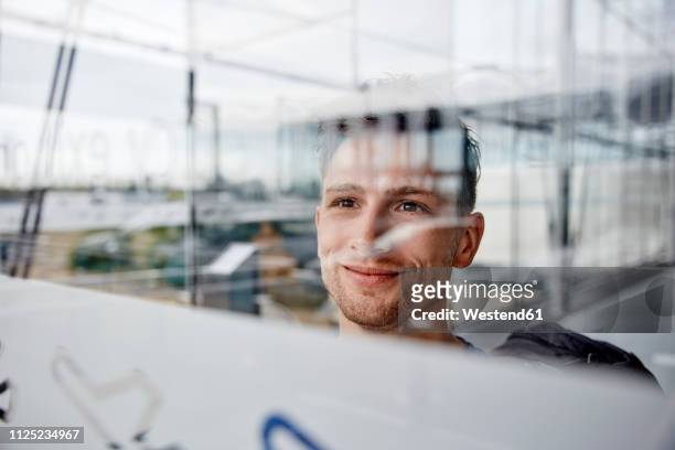 portrait of smiling young man at the airport looking out of window - effet miroir homme photos et images de collection
