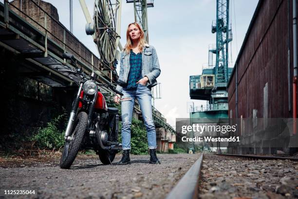 portrait of confident young woman standing next to motorcycle - adultes moto photos et images de collection