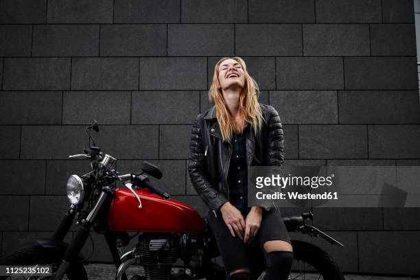 portrait of laughing young woman with motorcycle - solo una donna giovane foto e immagini stock
