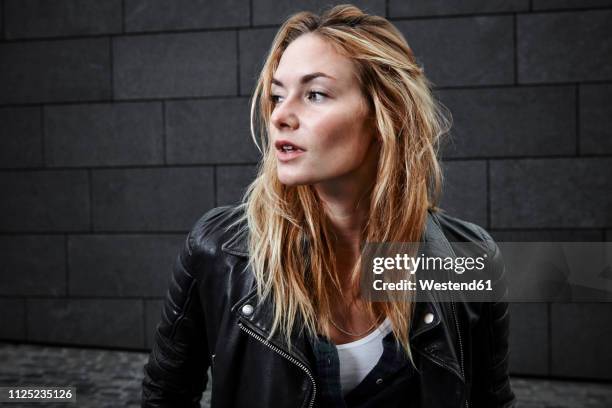confident young woman wearing biker jacket looking away - motorradfahrer stock-fotos und bilder