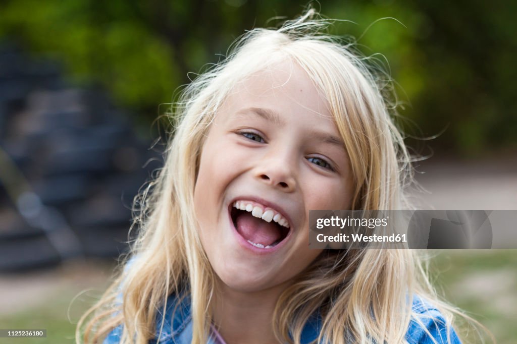 Portrait of laughing blond girl outdoors