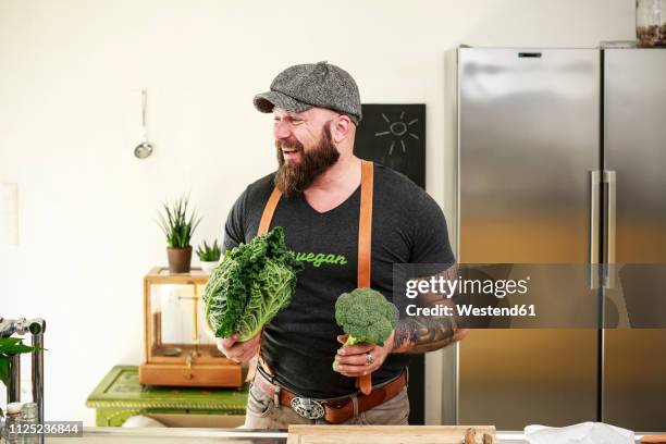 vegan man choosing vegetables in his kitchen - サヴォア ストックフォトと画像