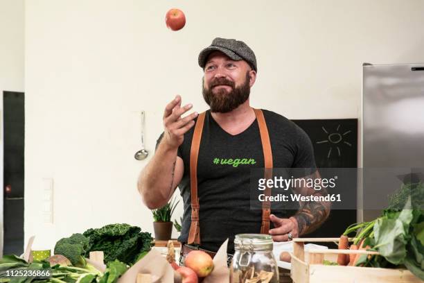 vegan man juggling with apples in his kitchen - ヴィーガン料理 ストックフォトと画像