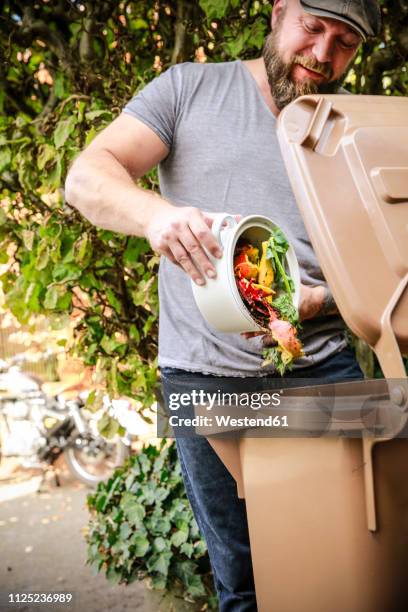 mature man throwing kitchen scraps into bio-waste container - mülleimer auf rollen stock-fotos und bilder