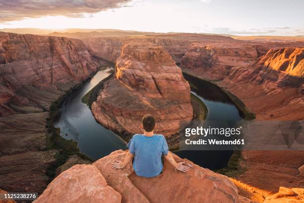 usa, arizona, colorado river, horseshoe bend, young man sitting on viewpoint - grand canyon nationalpark stock pictures, royalty-free photos & images