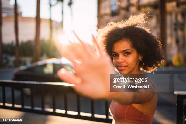 usa, nevada, las vegas, portrait of young woman in the city in backlight raising her hand - las vegas city people stock pictures, royalty-free photos & images