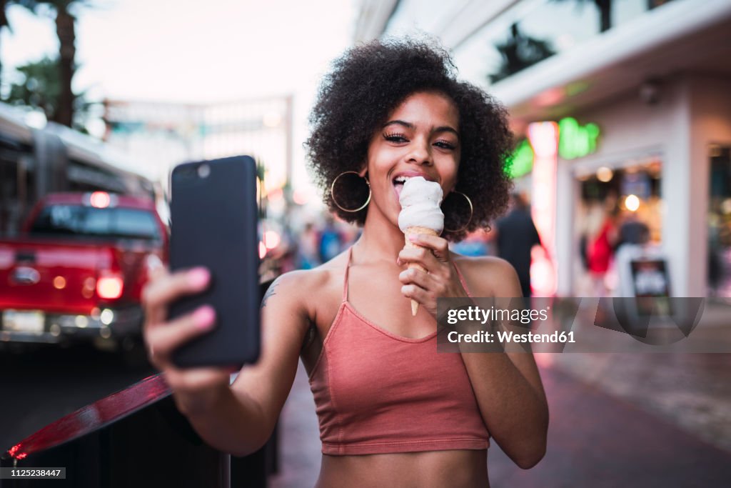 USA, Nevada, Las Vegas, happy young woman eating ice cream in the city taking a selfie