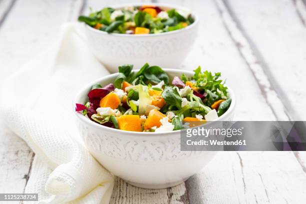 bowls of autumnal salad with feta and hokkaido pumpkin - salad bowl stock pictures, royalty-free photos & images
