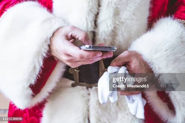 hand of santa claus text messaging, close-up - santa close up stock-fotos und bilder
