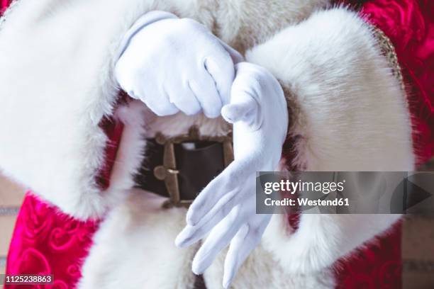 santa claus putting on his white gloves, close-up - santa close up stock-fotos und bilder