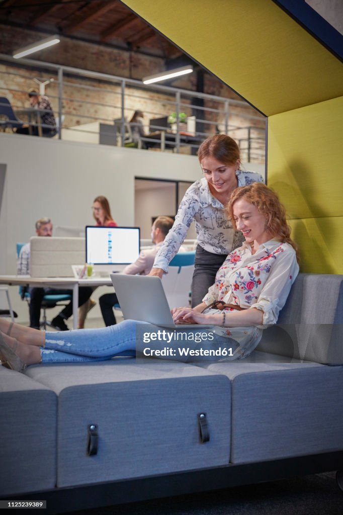 Young woman working in modern creative office, using laptop
